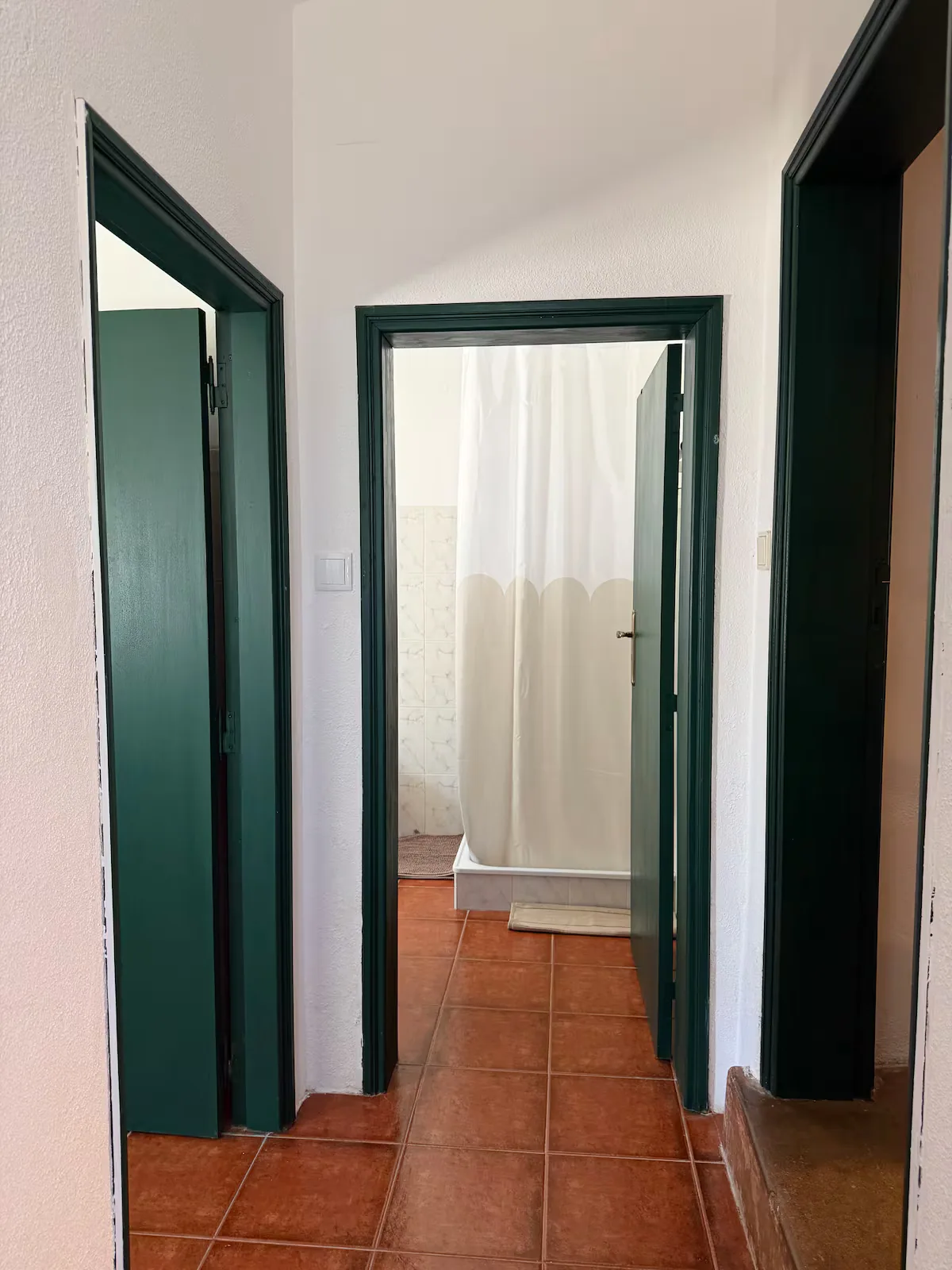 Corredor com portas verdes e chão de tijoleira